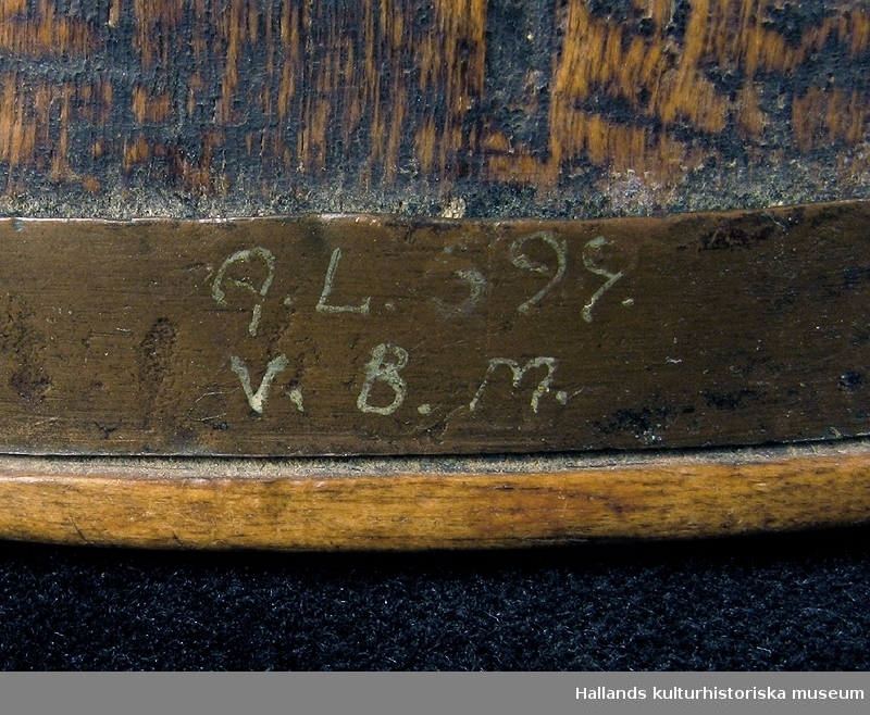Fnösketunna av trä. Utskuren. Band av metall i en kant med märkning. Text: "GL 599 V.B.M." (G? o 5?-osäkert)