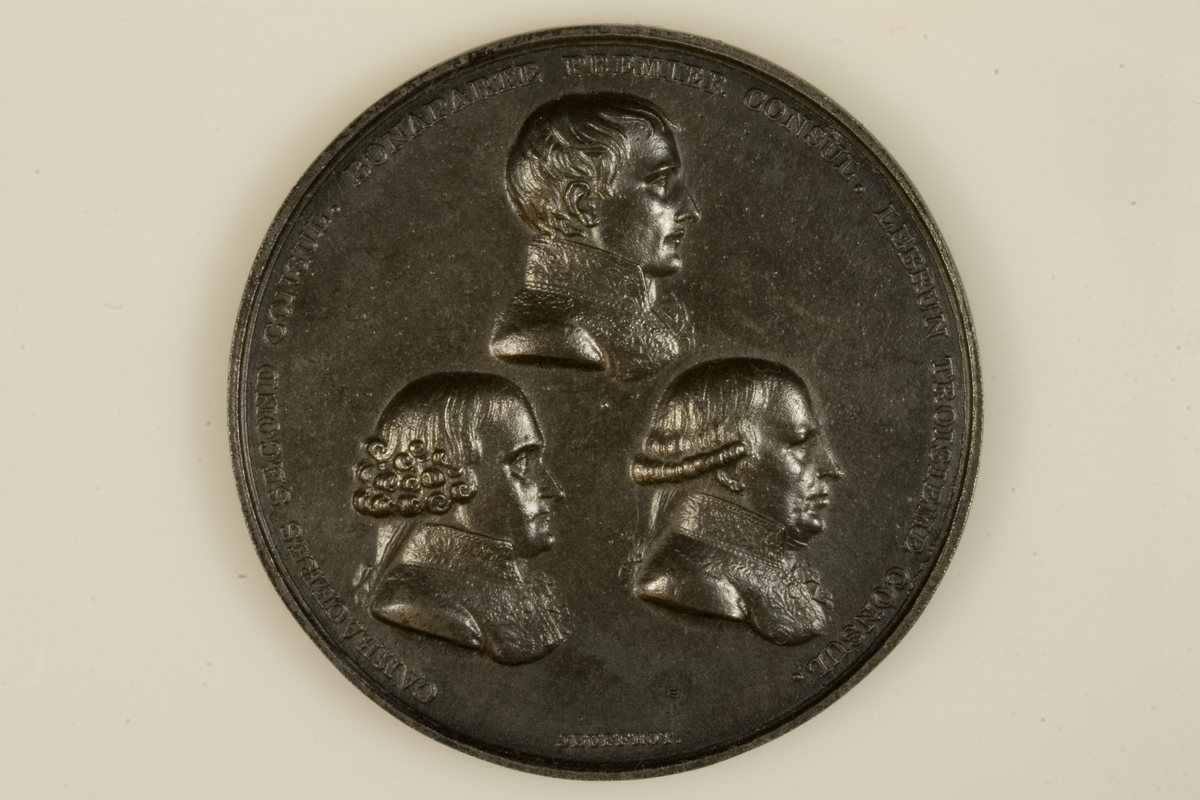 Motiv advers: Førstekonsul Napoleon Bonaparte over 2. konsul Cambaceres og 3. konsul Lebrun, alle byster i profil mot høyre.

Motiv revers: Tekst.