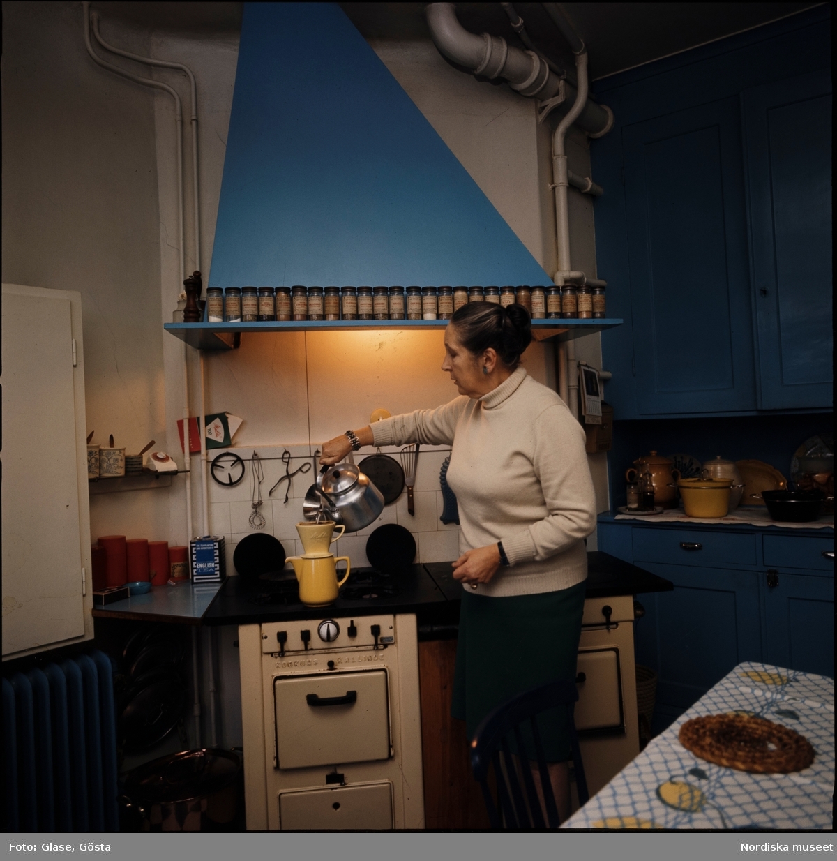 Kvinna brygger kaffe i ett kök.