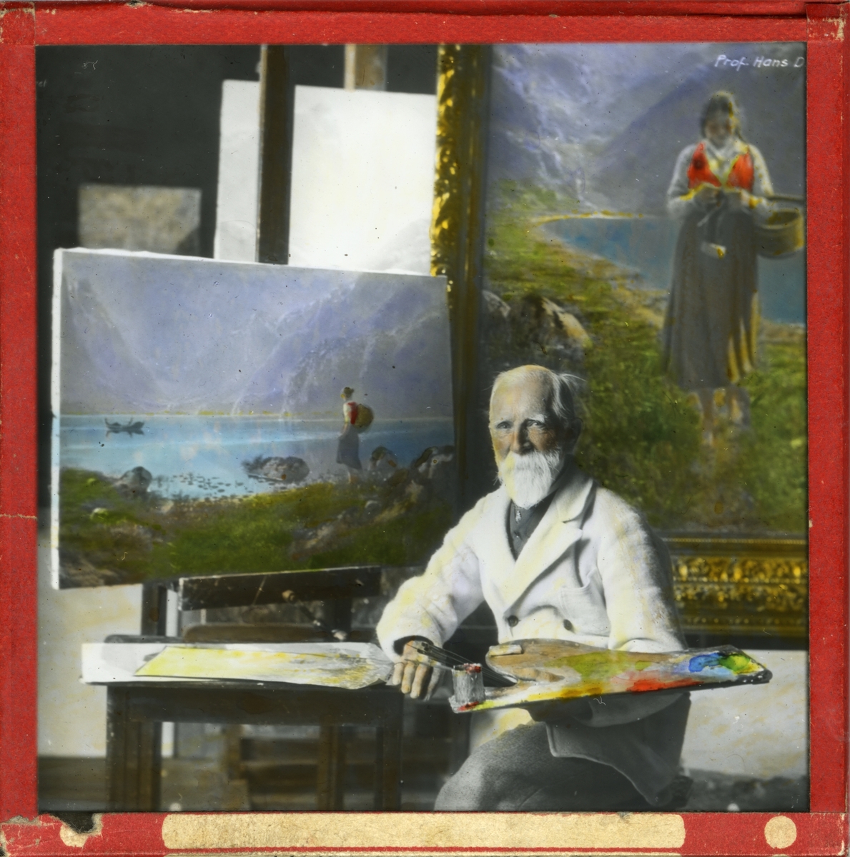 Håndkolorert lysbilde. Portrett av maleren Hans Dahl. Dahl sitter med palett og pensel i hånd foran et påbegynt maleri.