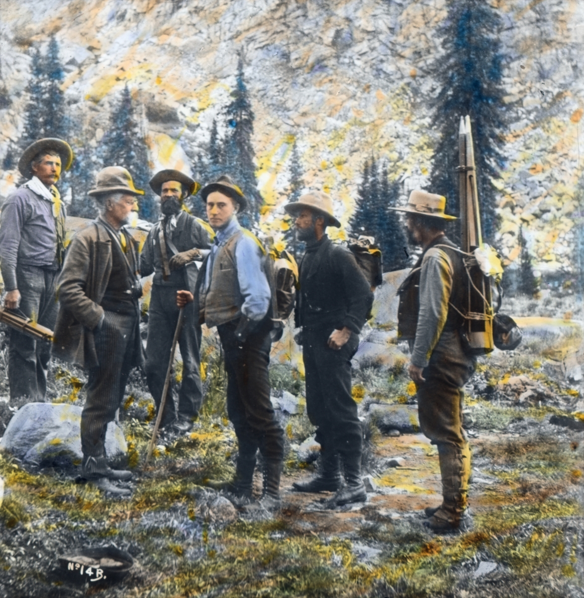 Håndkolorert dias. Seks menn utrustet med stativer og ryggsekker.  I boken "En emigrants ungdomserindringer" forteller fotografen Anders Beer Wilse om sitt arbeid i U.S.A, blant annet en ekspedisjon til områder utenfor Yellowstone nasjonalpark. Bildet er antakeligvis fra den ekspedisjonen.  