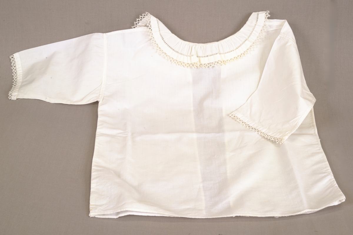 Hvit spebarnskjorte, kantet på krage og ermer med nupereller og hullfald.