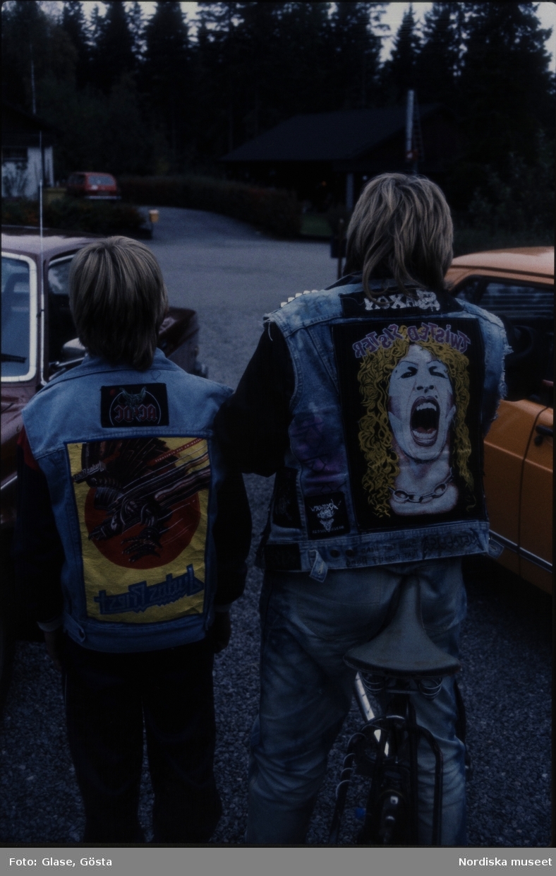 Två pojkar med dekorerade jeansjackor. Stora bilder och loggor från hårdrocksband påsydda på ryggarna.