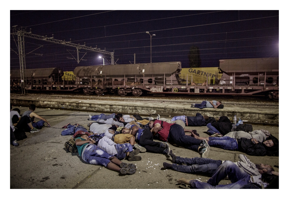 Flykninger og migranter sover på togplattformen på togstasjonen i den makedonske grensebyen Gevgelija. Flere hundre venter på et morgentog som går klokken 05.00 og vil ta dem gjennom Makedonia og til grensen mot Serbia. Tidligere samme natt krysset de grensen mellom Hellas og Makedonia ulovlig. Før de får ta toget må de registrere seg hos politiet for å få reisedokumenter.