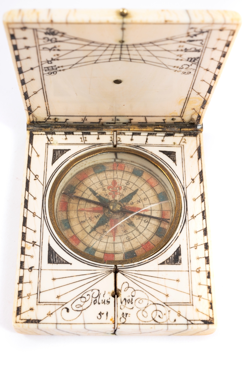 Solur i fodral av ben. Kompass med ros i rött och blått. Inskription: "Polus Höe 51 gr." På locket kalendarium visande månens gång.