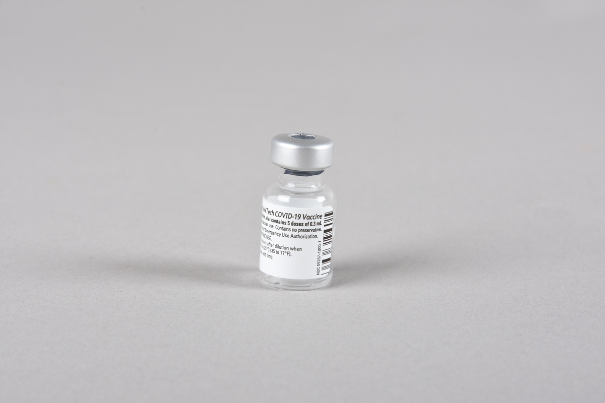 Vaksinasjonsutstyr brukt ved første vaksine mot Covid-19, satt i Bergen 05.01.2021. Utstyret består av en engangssprøyte med kanyle og beskyttelseshette og et åpnet hetteglass for Pfizer-vaksine, med tilhørende kork.