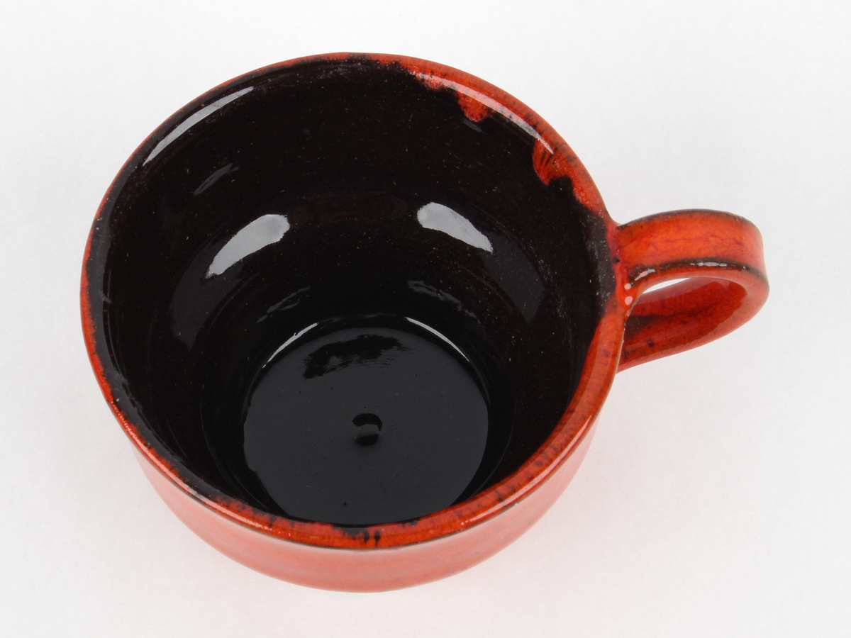 Uranrød kopp med hank med sort glasurkant.