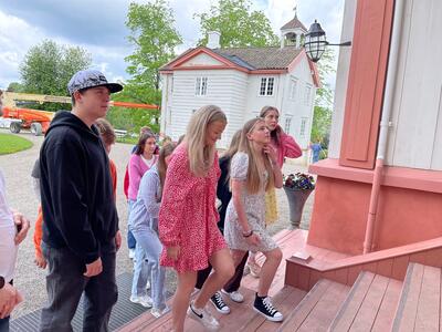 Ungdomskoleelever fra Vestlandet ikledd sommerklær går opp trappa mot inngangsdøra til Eidsvollsbygnigen