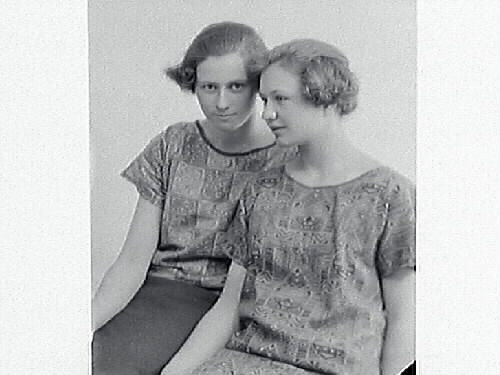 Ateljéporträtt av två unga kvinnor i modernt korta frisyrer och mönstrade blusar. Lissie Hjalmarsson beställde bilderna och är troligen en av kvinnorna.