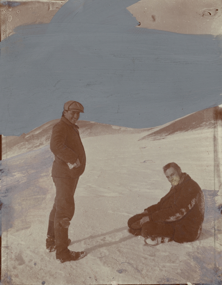 Fotografi från första svenska Antarktisexpeditionen 1901-1904. Motiv av två män i snölandskap. Till vänster står José Maria Sobral och till höger är Otto Nordenskjöld.