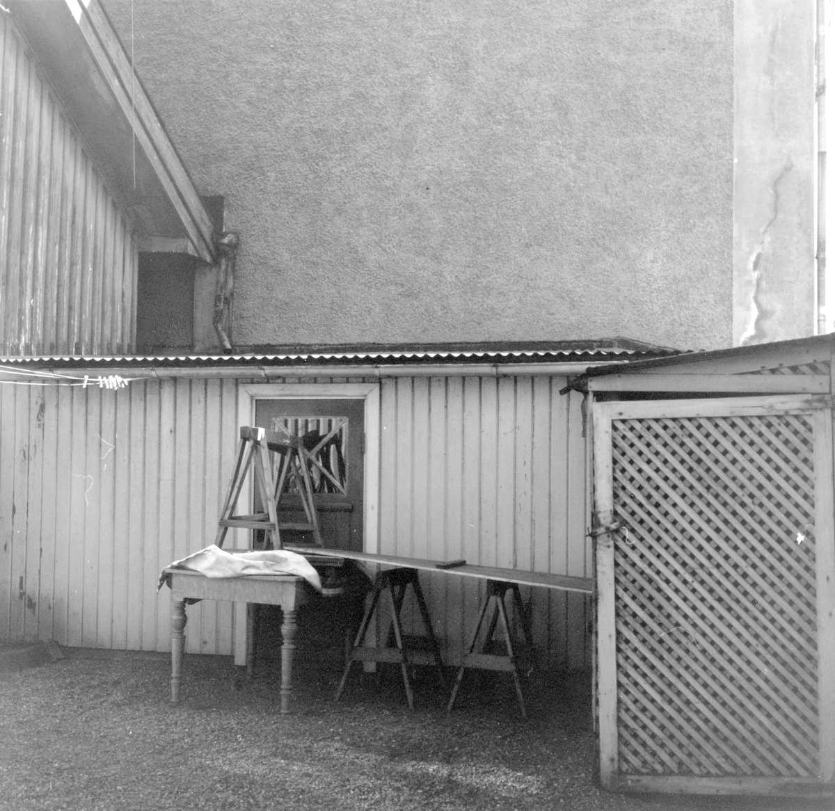 Bord och bockar utställda längs ett uthus på innergård i kv Alströmer.