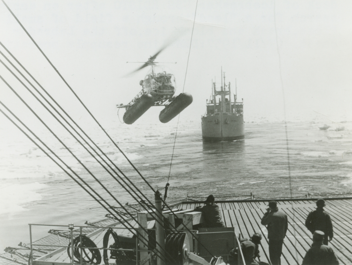 Diverse bilder från Fred Goldbergs samling. Motiv av en helikopter modell HTL-5 som är på väg att landa på flydäck tillhörande isbrytaren USS Edisto. Bilden är tagen 7/11-1957.