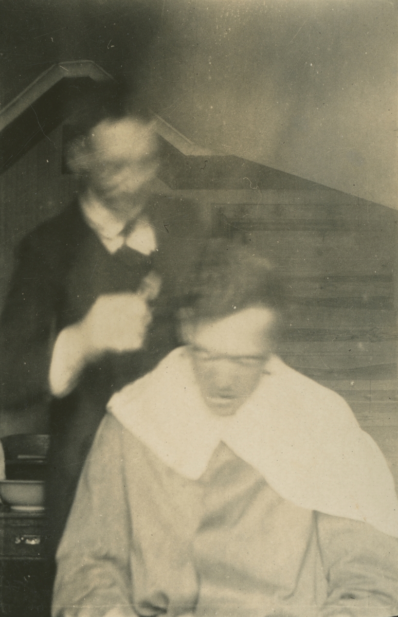 Fotografi från expedition till Spetsbergen. Motiv av man som får sitt hår klippt av en annan man.