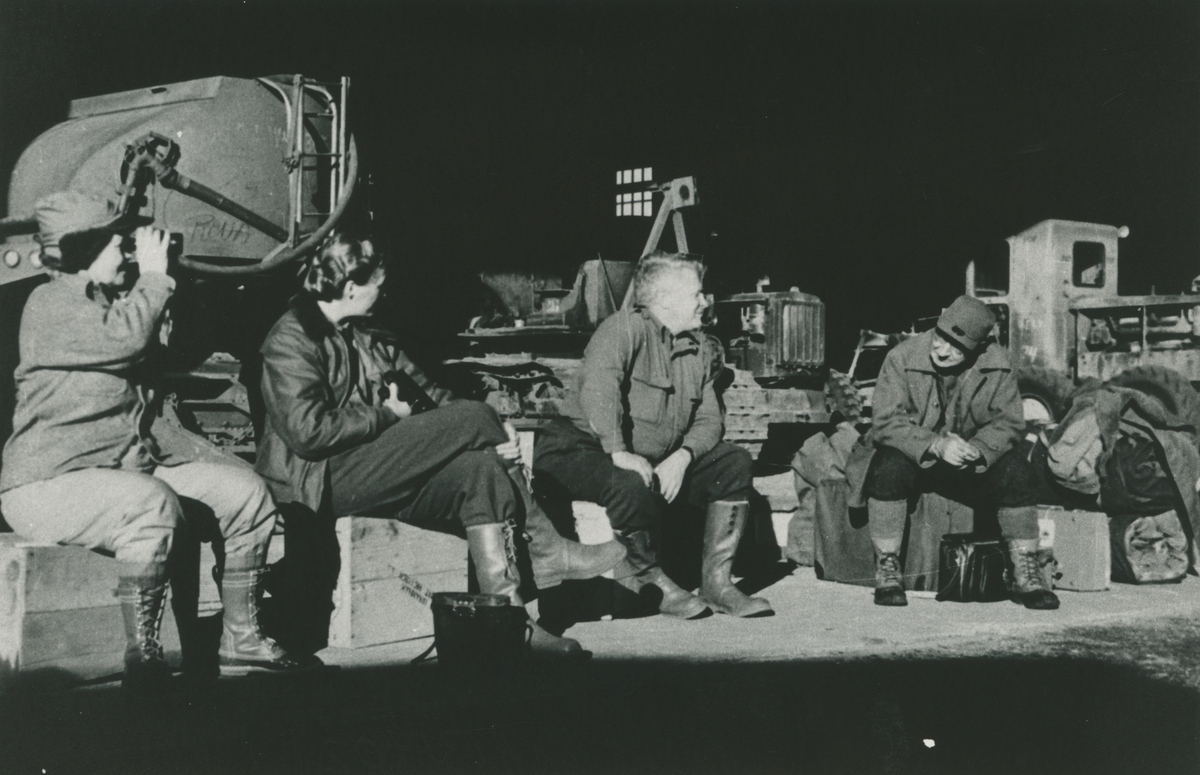 Fotografi från låda märkt Bernt Balchen. Balchen var norsk-amerikansk flygare, polarforskare och militär. Motiv av Bernt Balchen med tre andra expeditionsdeltagare som vilar bland packning. Balchen är mannen i mitten.
