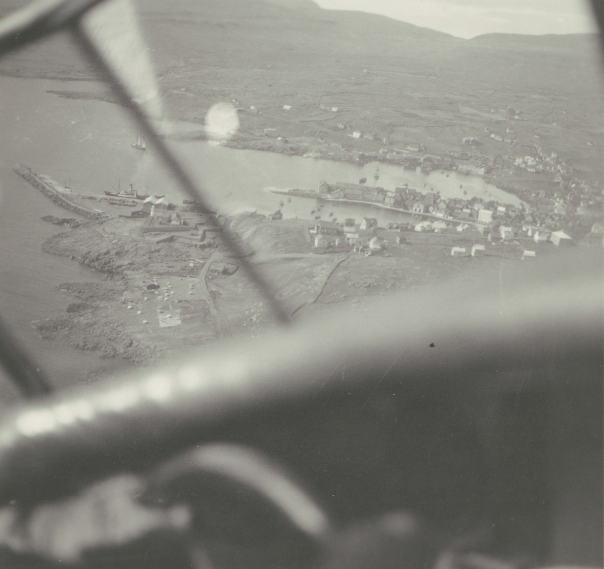 Fotografi från Albin Ahrenbergs resa till Grönland 1929. Vy över liten kuststad i bergslandskap.
