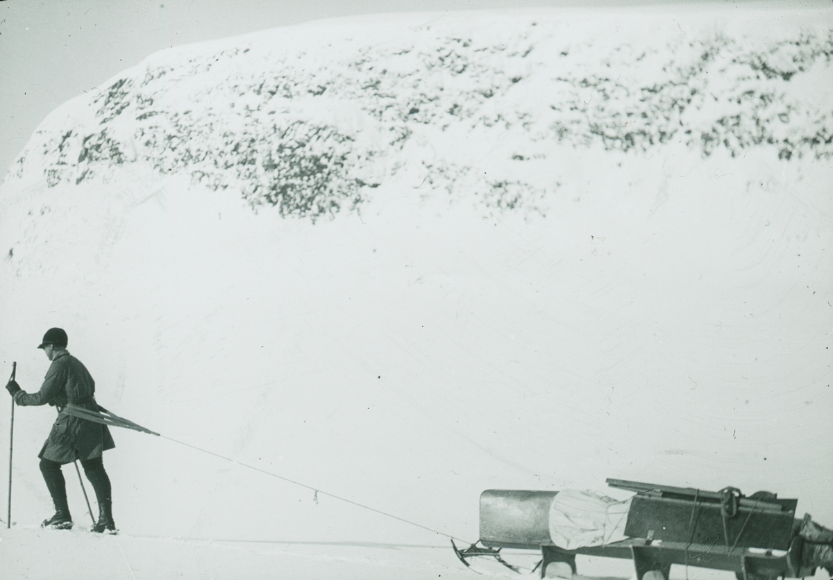 Fotografi från expedition till Spetsbergen. Motiv av man som drar packning i snölandskap.