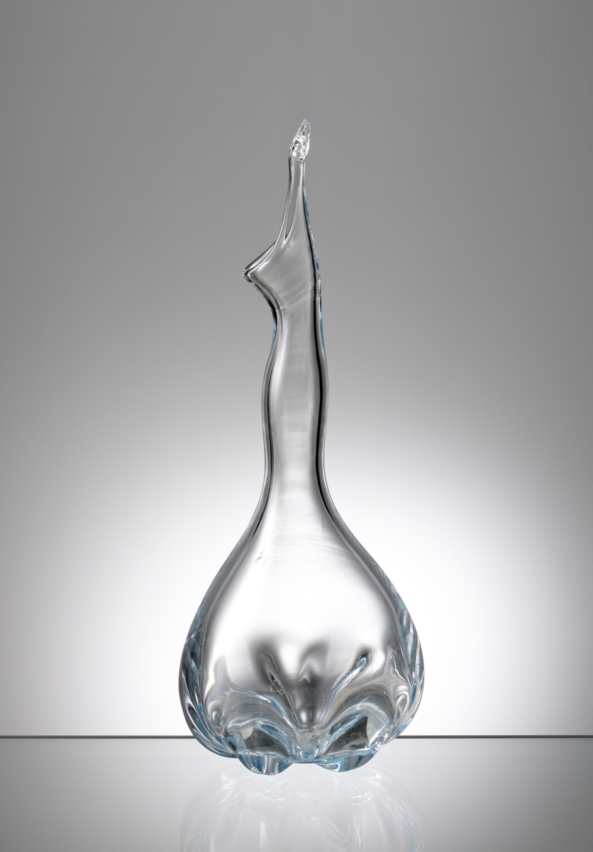 Formgiven av Edward Hald. Ljusblå, kalebassformad vas med klämd botten. Lång, spolformad hals och mynning med "snip".
Puntelmärke i botten.