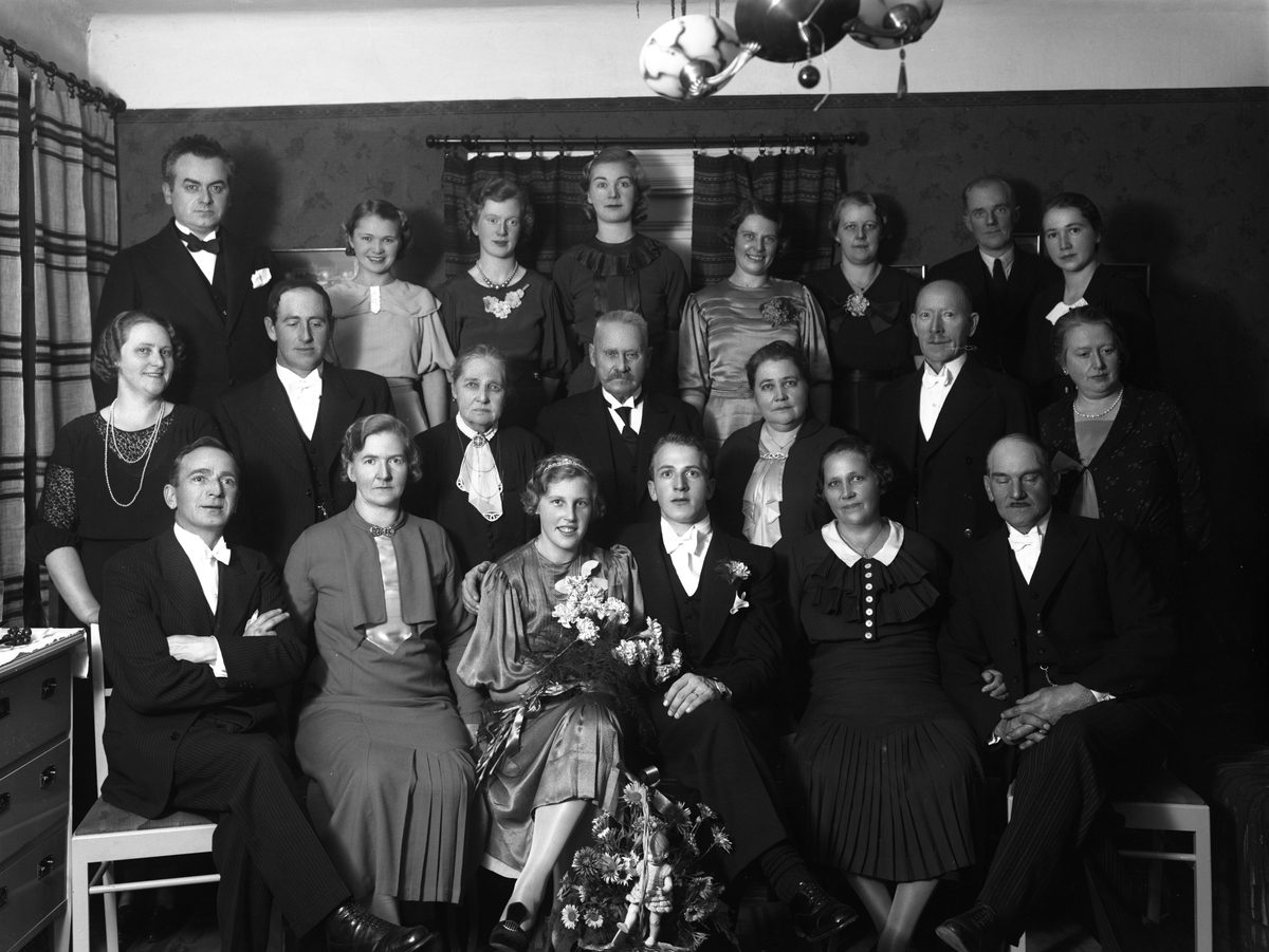 Den 17 oktober 1936 sammanvigdes Bertil Lundin och Mary Tornström i Linköping. Vid tiden arbetade Bertil som tapetserare och Mary som biträde vid ett av stadens bagerier. Här ser vi dem i kretsen av familj och släkt kort efter vigselakten. Platsen är brudens föräldrahem på adressen Badhusgatan 4.