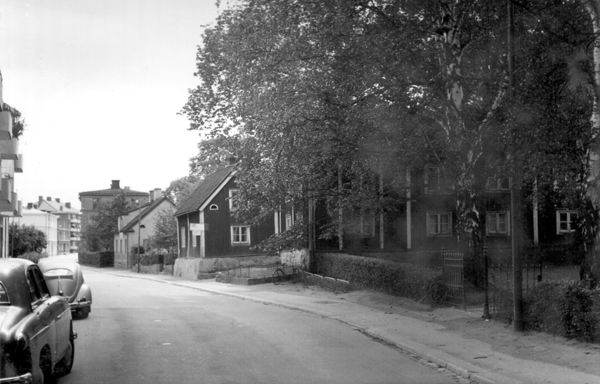 Barnhemsgatan i Linköping sedd mot söder. Gatan har fått sitt namn efter det barnhem för flickor som från 1866 låg utmed vägen till vänster strax utanför bilden. Träkåkbebyggelsen till höger ingick i den så kallade Sotargården. Odaterad bild från omkring 1960.