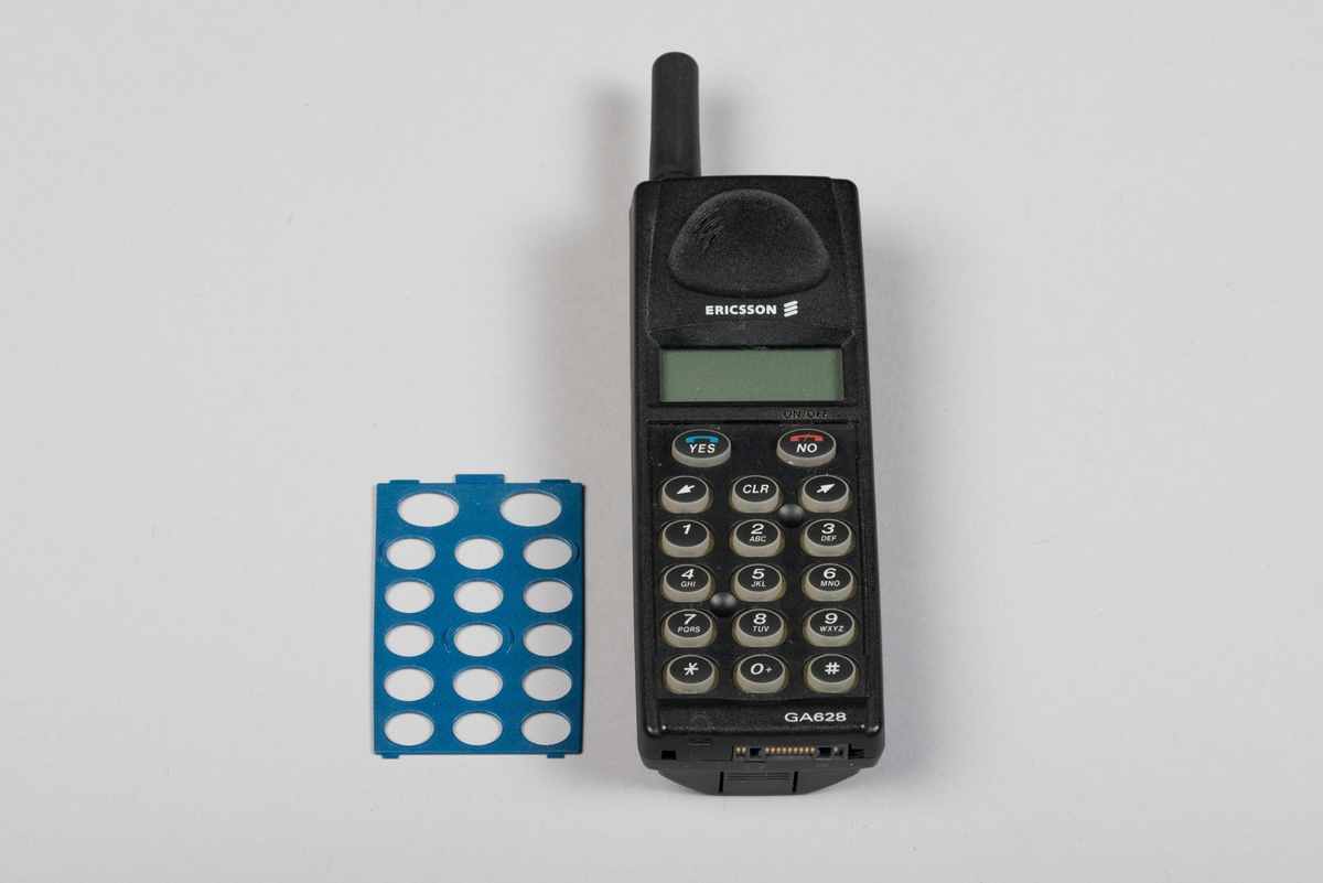 Mobiltelefon i svart plast med löstagbar blå frontpanel. Telefonen har en display och en antenn. Bakstycket utgörs av ett löstagbart batteri. Innanför bakstycket finns en simkortshållare.  Kontakt för laddare finns på telefonens undersida. Bredvid antennen sitter en lysdiod.