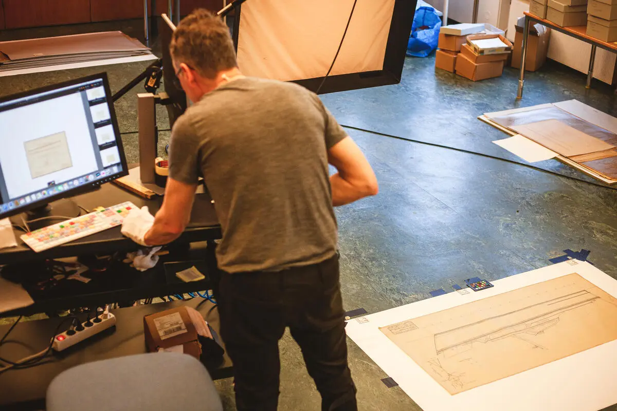 Fotografering av Scheens båttegninger. Fotograf Ulf Palm sjekker resultatet på skjerm.