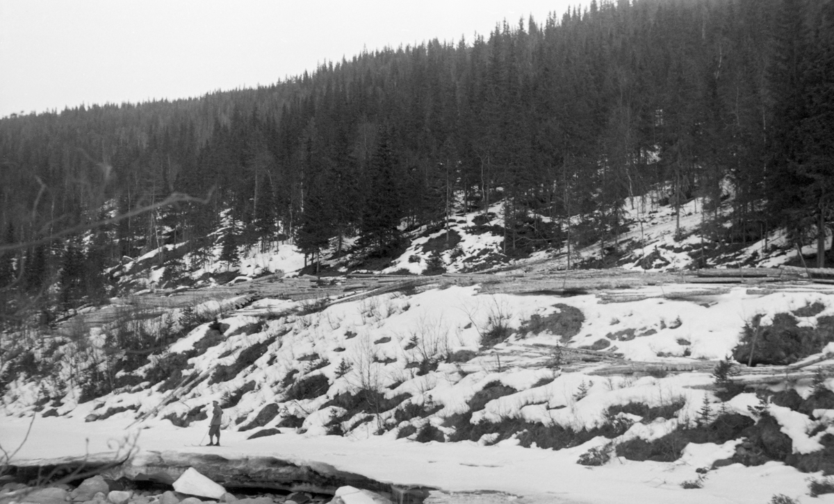 Tømmertillegging på snøen ved Vinstravassdraget i Nord-Fron i Gudbrandsdalen. Fotografiet ble tatt i april 1954. Det viser hvordan tømmerkjørerne i løpet av foregående vinter hadde kjørt tømmer ned på elvebrinken, der de hadde veltet det av i såkalte lunnevelter - som fyrstikker i en eske. Stokkene lå parallelt med strømretningen i elva nedenfor. Når snøen og isen var borte og elva hadde fått høvelig vannføring, ble stokkene rullet nedover den snauhogde elveskråningen. Deretter var det meningen at oppdriften og strømmen i vannet - med litt bistand fra fløterne - skulle bære tømmeret nedover mot Gudbrandsdalslågen, og kanskje videre over Mjøsa og nedover Vorma og Glomma. Vegen tømmerkjørerne hadde brukt nedover den bratte lia mot velteplassen skimtes til høyre i bildet.