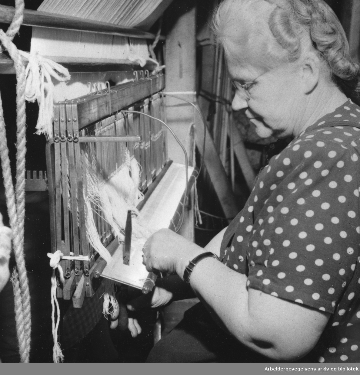 "Hjula - fabrikk med tradisjoner. Bertha Bagge sitter ved "skjeen": vevtrådene skyves sammen slik at veven blir tett". Billedreportasje fra Hjula Væverier i Magasinet for Alle, september 1954.
