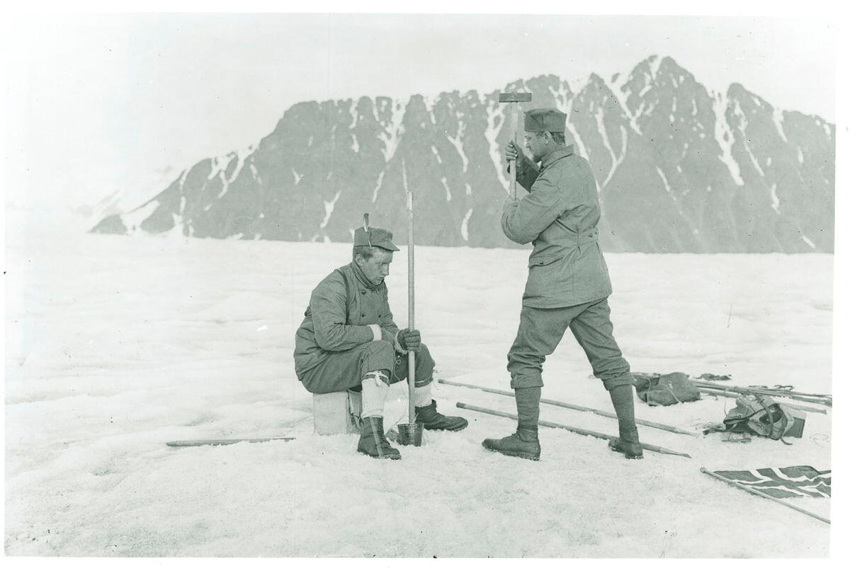 Bildet viser Adolf Hoel som slår ned en teltstang på Liliehøkbreen i Kongsfjorden.