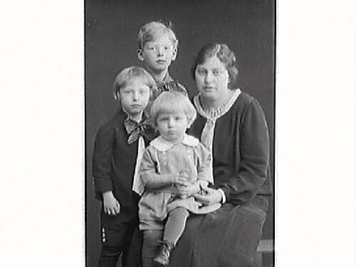 Komminister Aronius fru och tre söner. Barnen bär kortbyxor, strumpor och skor. Den minste är klädd i kolt med de två äldre har korta rockar, västliknande skjortor och stora halsrosetter.