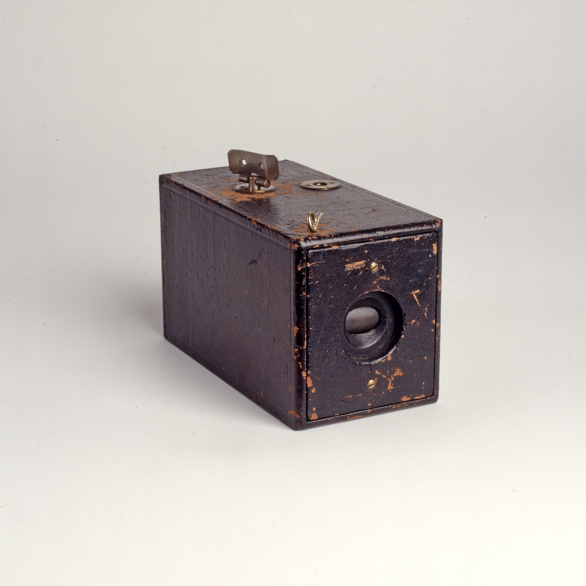 Eastman Kodak Company, grunnlagt av George Eastman (1854-1932), ble etter hvert giganter på kamera og film. Målsetningen til selskapet var å gjøre fotograferingen enklere og mer populært, blant annet ved å introdusere kameraer som var lette å håndtere. Et av slagordene som selskapet brukte, var: «you push the button, we do the rest». «The Kodak» ble patentert den 4. september 1888, og skulle gjøre det mulig for folk uten teknisk kompetanse å ta bilder og skape minner for livet. 
Dette var det første kameraet som brukte rullfilm (mot den rådende glassplaten), og dermed en hel revolusjon i fotografiets historie. Kameraet hadde ingen muligheter for innstilling, og heller ingen søker å se gjennom for å sjekke motivet, kun en vinkel risset inn på oversiden av kameraet som indikerte retningen. Bildene som ble produsert med disse kameraene var runde, lik linsens utsnitt, og et trill rundt bilde skjuler skjeve horisonter og gjorde det til en takknemlig oppgave for amatører å fange verden i et bilde. 