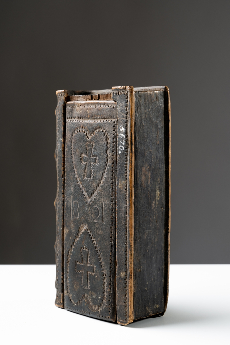 Skrin, "brudlåda", av svartmålat trä i bokform försett med skjutlock. På fram- och baksida dekor av hjärtan med kors inuti. På framsidan inristat: "1821", på baksidan: "ANNO".