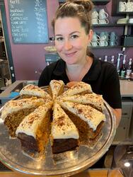 Kvinne ansatt i Kafe Standpunkt viser fram ei kake