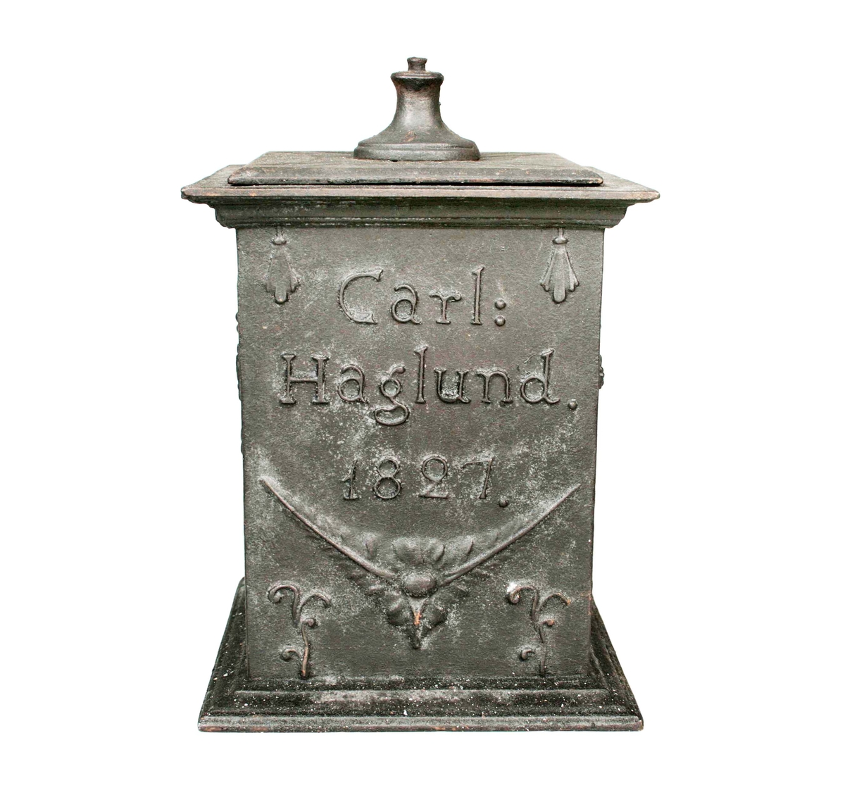Fyrsidig med lock (defekt, lockurnan saknas). Sidorna med reliefdekor av "offeraltare, segergudinna, samt namnet Carl Haglund 1827". Under locket märkt: "HF" (Hällefors bruk).