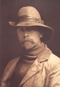 Edward S. Curtis, selvportrett 1899. Bilde av Curtis ikledd klær fra slutten av 1800-tallet, han har bart og skjegg, og han har en hatt på hodet.