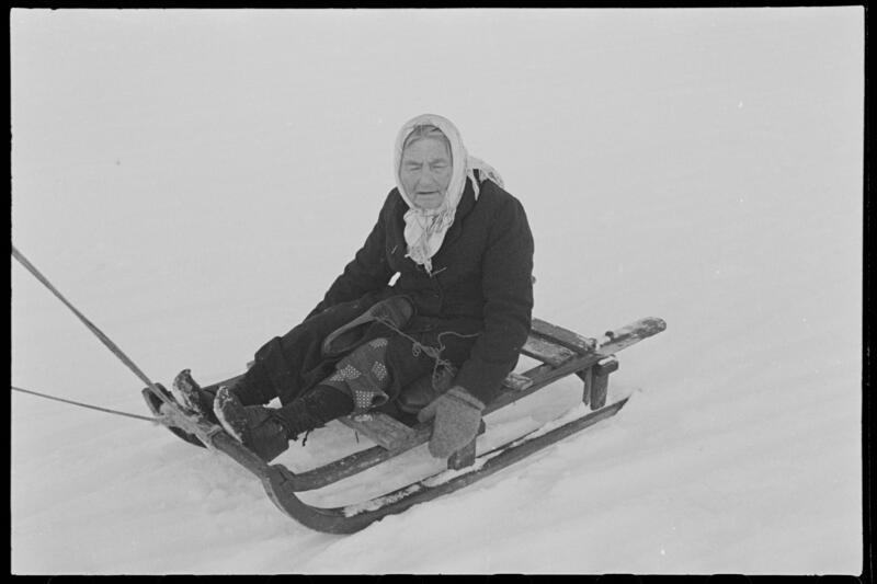 Eldre kvinne på kjelke, vinteren 1945 på Sørøya, Hammerfest kommune.