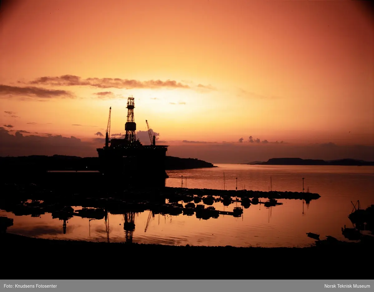 Oljeriggen Scarabeo liggende til kai i Dusavik med solnedgang i bakgrunnen.