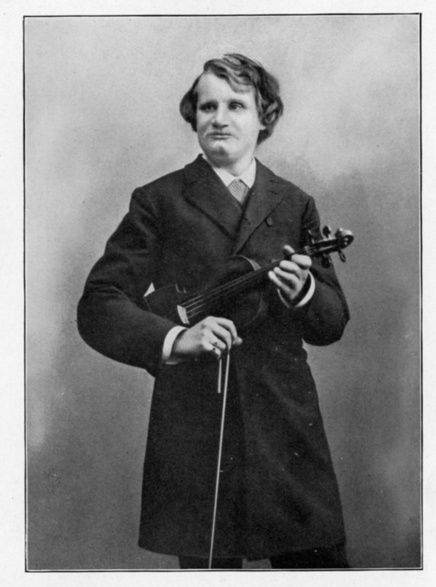 Portrettfotografi av fiolinist Henrich de Ahna. Han holder en fiolin og bue i hendene.