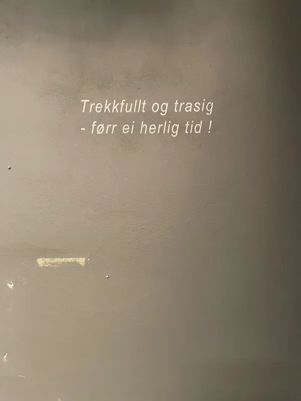 Det står "Trekkfullt og trasig -- førr ei herlig tid!" på veggen.