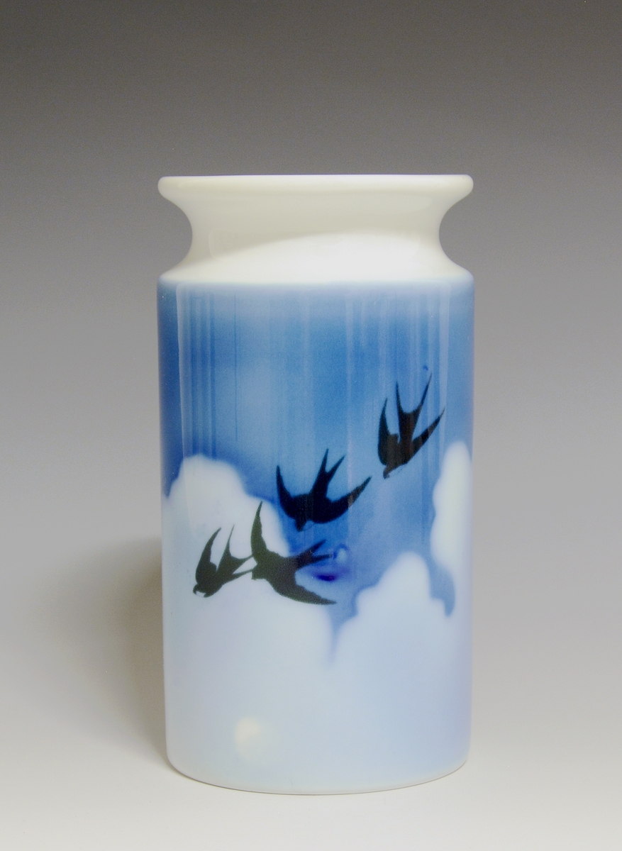Vase i porselen. Dekorert med svaler mot skyer og blå himmel på to sider i underglasurdekor.

Kunstner: Eystein Sandnes