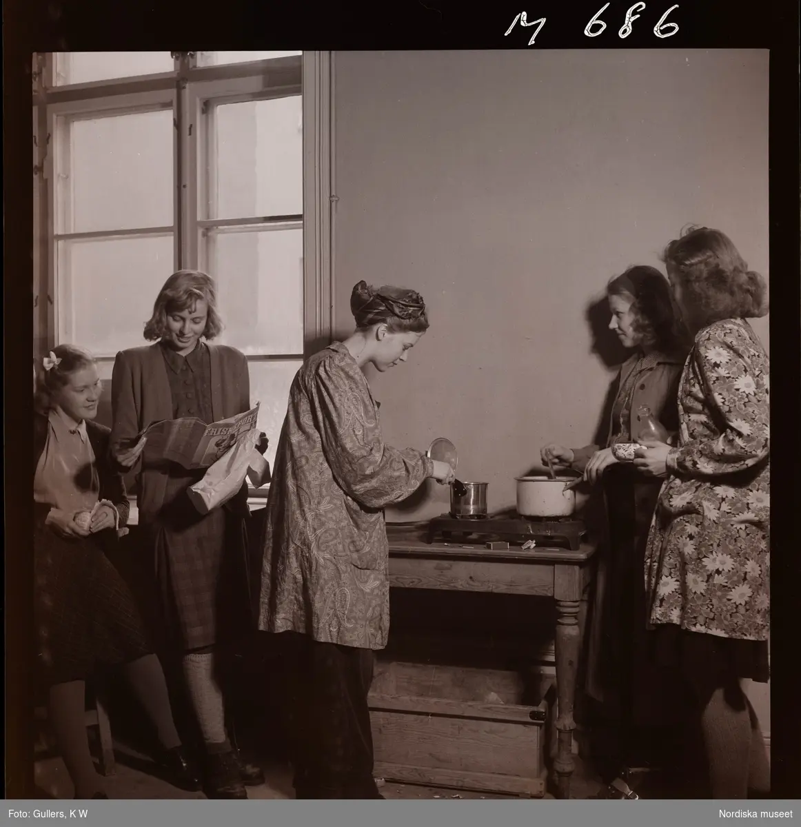 1677 Konstfackskolan. Lunchpaus/rast. Kvinnliga elever värmer mat på kokplatta.