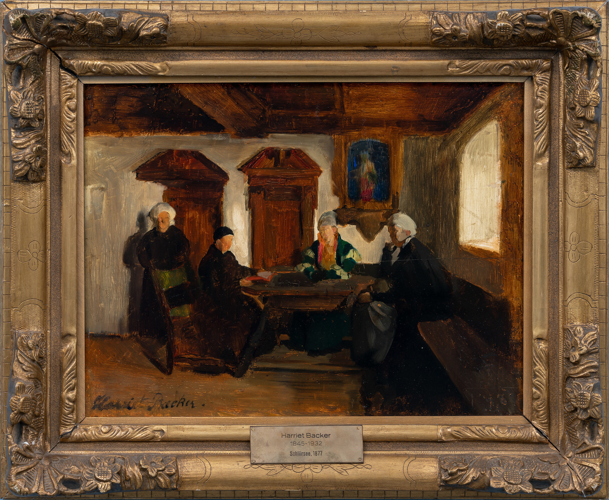 Tre kvinner og en mann er samlet rundt ett bord i en enkel stue, med lys fra ett vindu til høyre. 