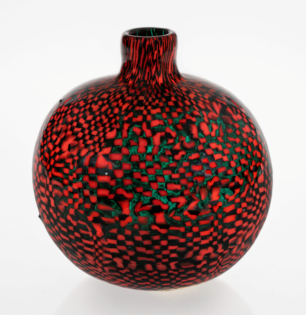 Kuleformet vase i murrineteknikk, utført i polykromt glass. Kort sylindrisk hals. Overflaten består av rødfarget opakt glass som kontrasteres med gjennomskinnelig grønt glass.
