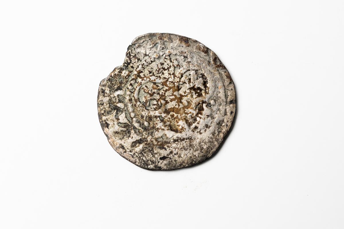 Ett silvermynt, örtug, präglad i Visby. På ena sidan staden Visbys märke och på den andra den tyska liljebusken.