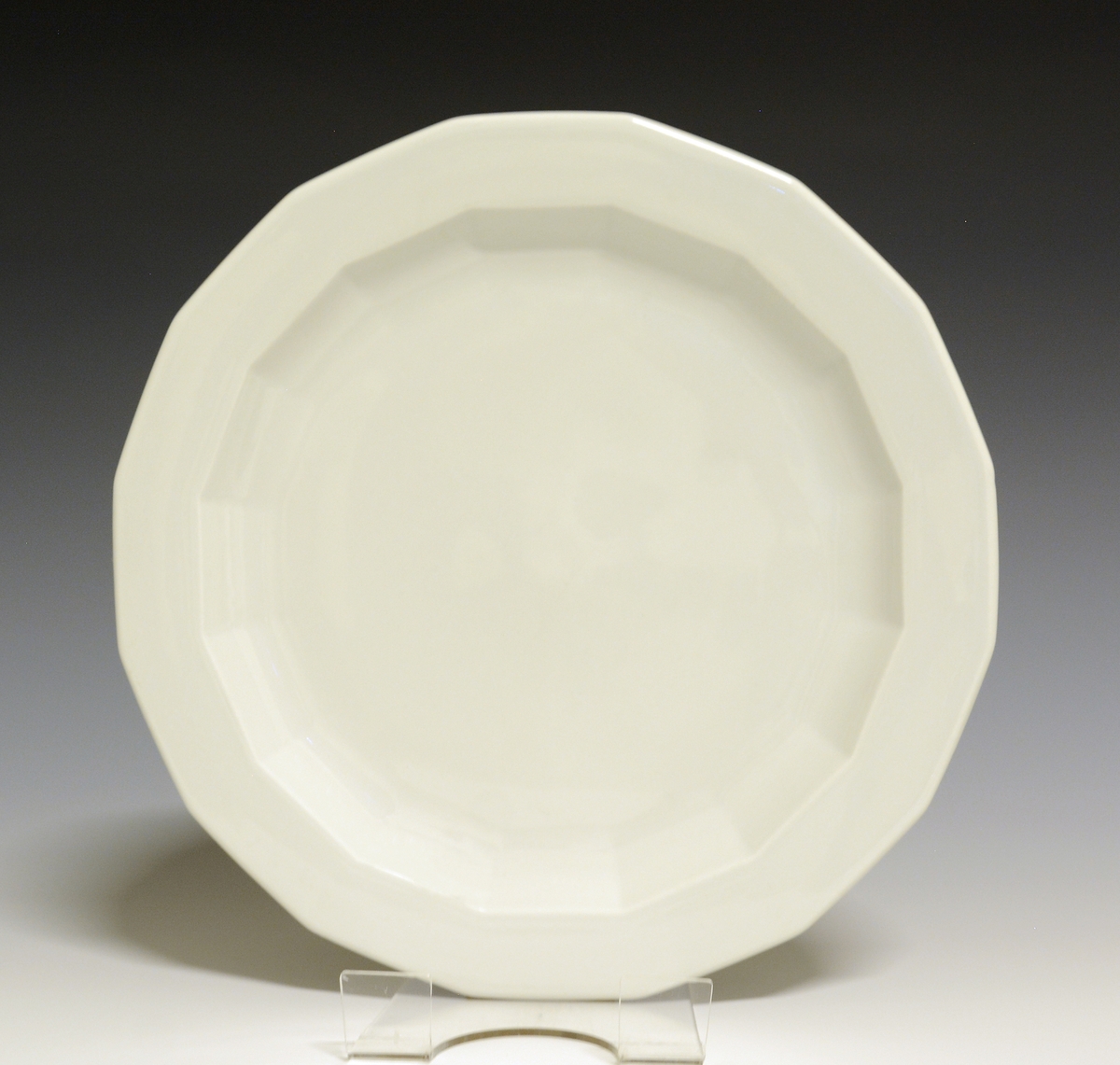 Mangekantet tallerken av porselen med hvit glasur. 
Modell: Octavia, tegnet av Grete Rønning i 1977.