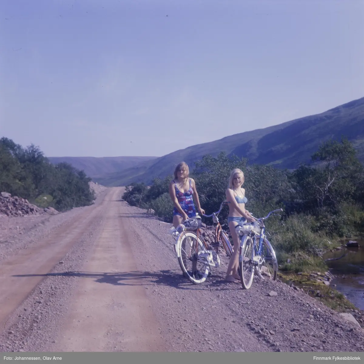 Foto av bilvei omringet av bjørkeskog, trolig Syltefjorddalen

To jenter står i badedrakt ved siden av hver sin sykkel

Foto trolig tatt på 1960/70-tallet