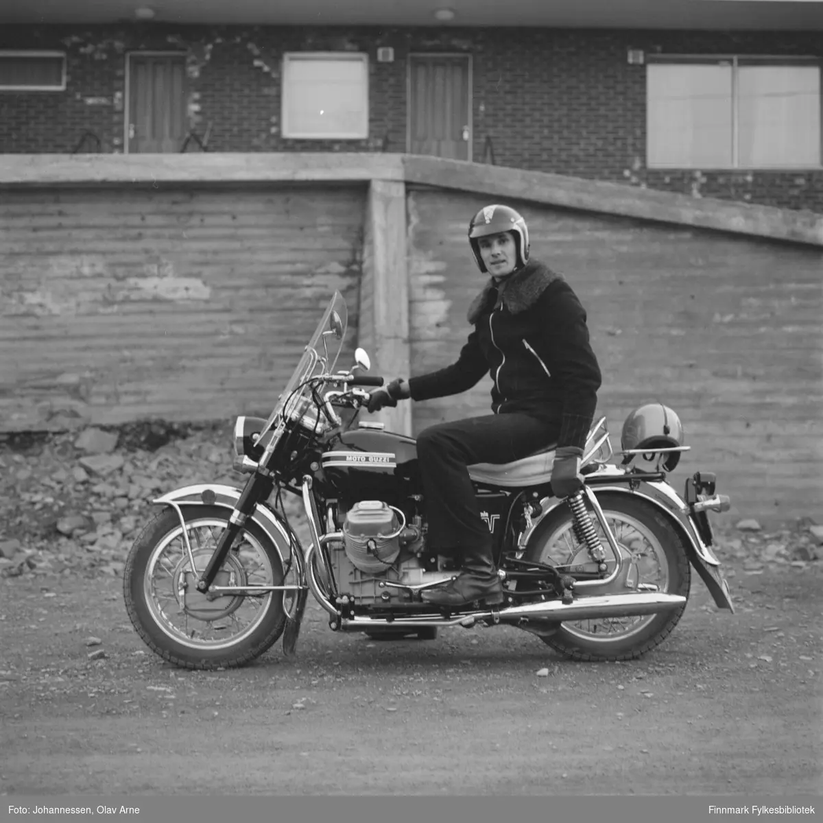 Dag Antonsen sitter på motorsykkel, modell Moto Guzzzi

I balgrunnen kan man se Åttemannsboligen øverst i Klausjorda

Påskrift: Bilde viser Dag Antonsen med sin  nye motorsykkel 