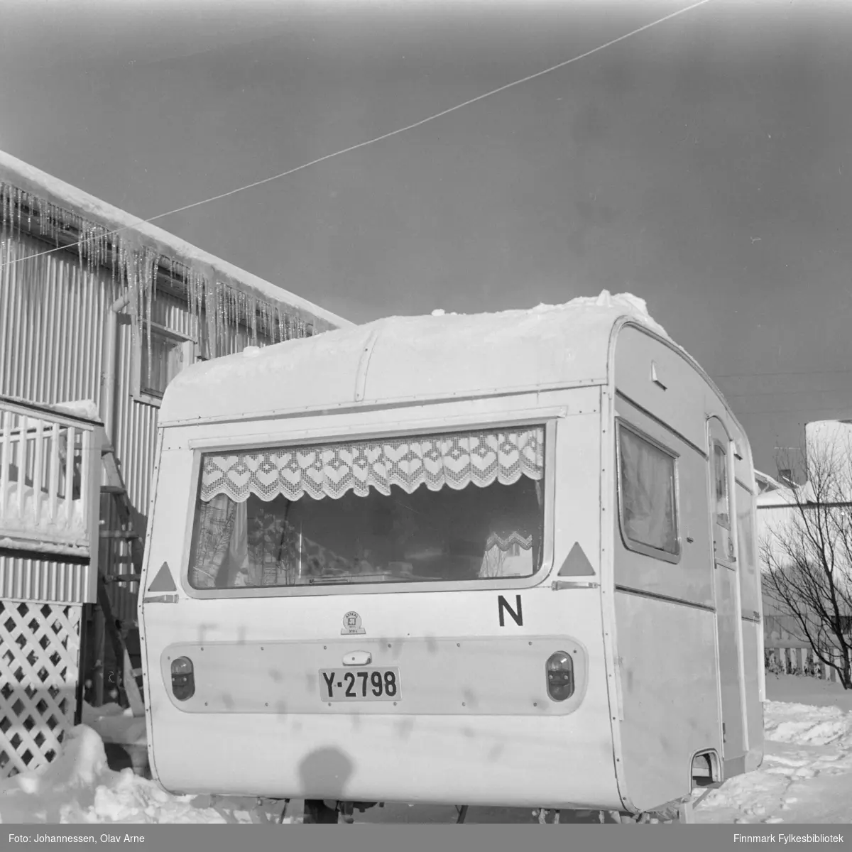 En campingvogn står parkert ute i snøen. Vognen har skiltnummer Y-2798