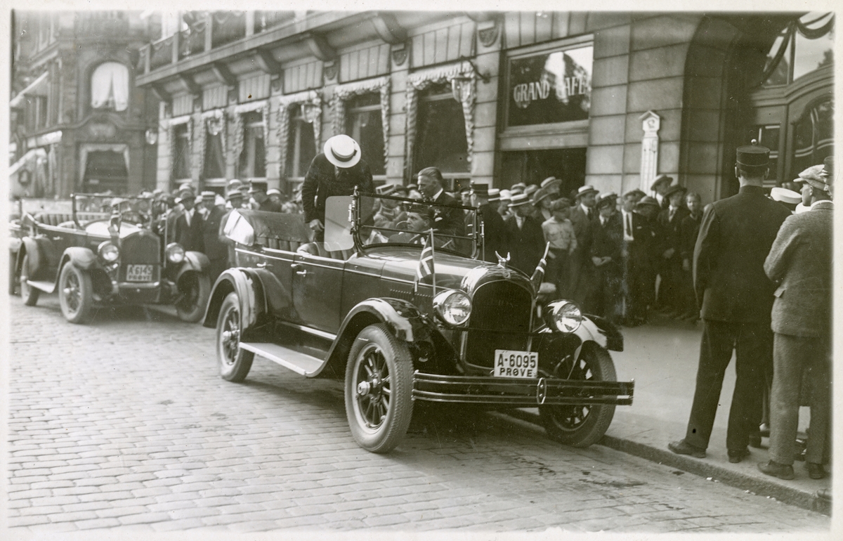 Ekspedisjonsdeltager stiger opp i åpen bil i bilkortesje i Karl Johans gate v/Grand Hotel, omgitt av mange tilskuere - Roald Amundsens ankomst til Oslo med S/S "Bergensfjord" efter "Norge"s færden over Polen - 16. juli 1926.