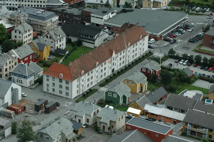 Oversikts bilete over Folgefonn gata i Odda. Ein kan sjå dei fargerike arbeidarboligane og museumshagen til høgre i bilete, rett overfor til venstre i bilete ser ein murboligen. Foto.