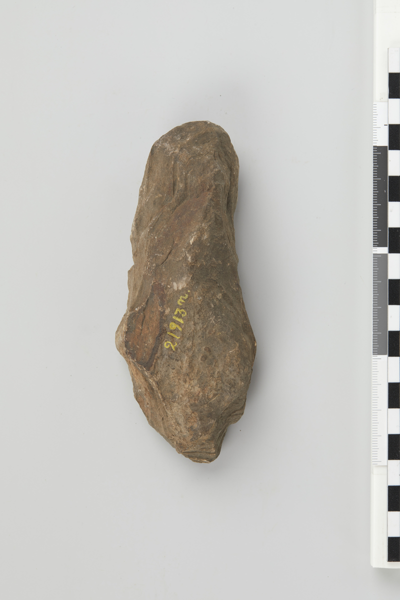 Emne til stenöks av Nöstvettype, ujevnt dannet. Længde 13,4 cm, störste bredde 5,5 cm.